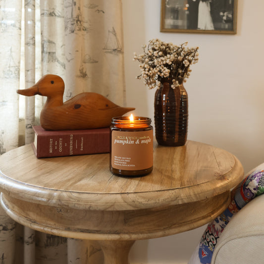 Candle on a wooden table with decorative items in a cozy room.