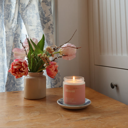 Candle and flowers on a table with a window in the background